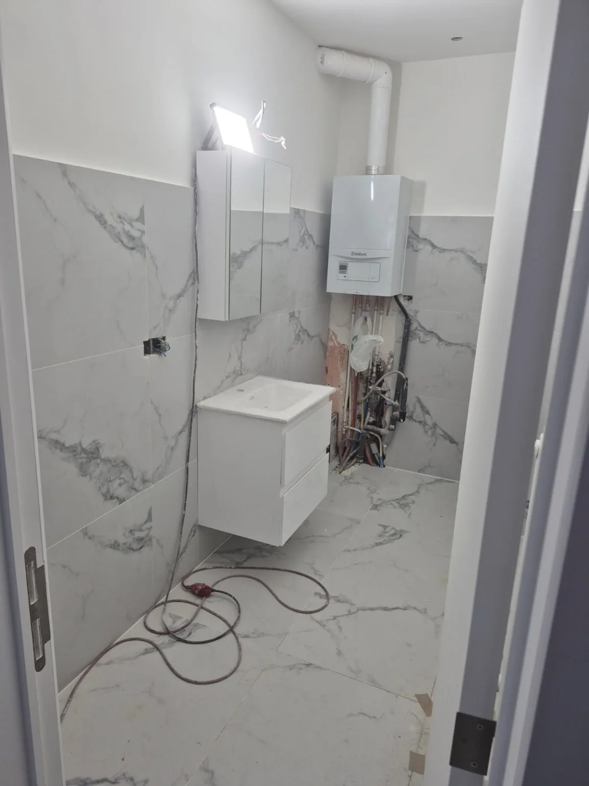 Salle de bain après pose du carrelage et du meuble ; raccordements encore à terminer